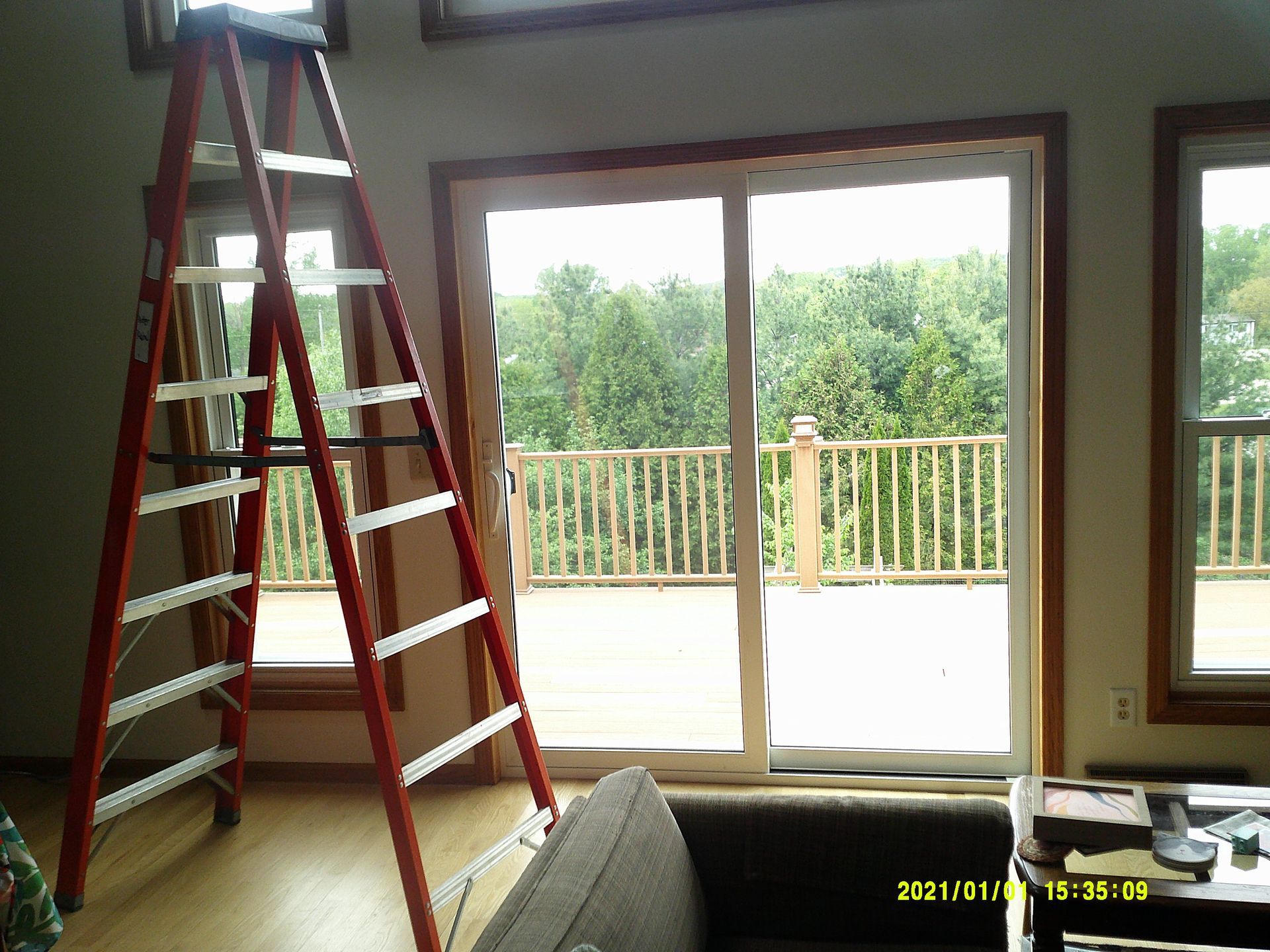 A living room with a ladder and a sliding glass door