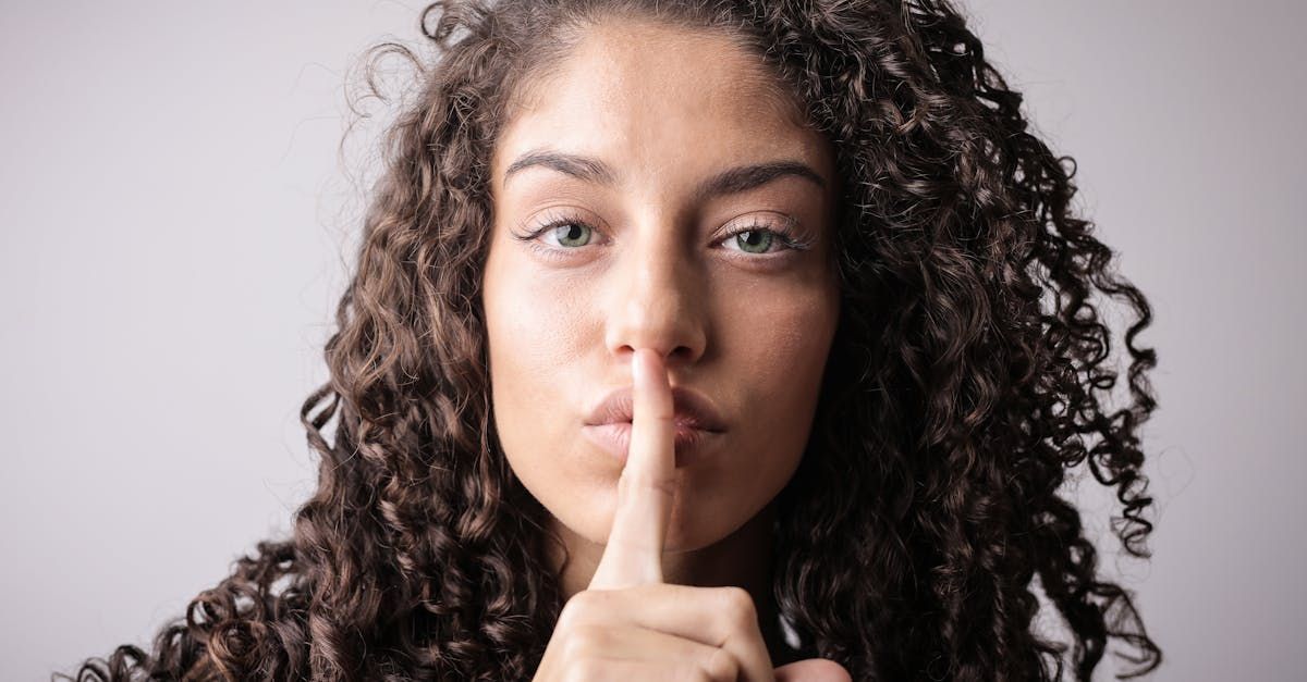 A photo of a lady holding her finger to her lips suggesting the keeping of a secret