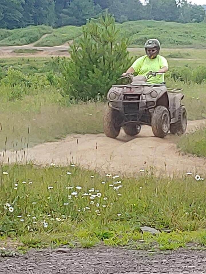 A man is riding an atv on a dirt road.