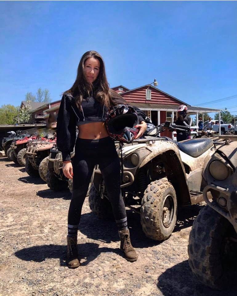 A woman is standing in front of a row of atvs