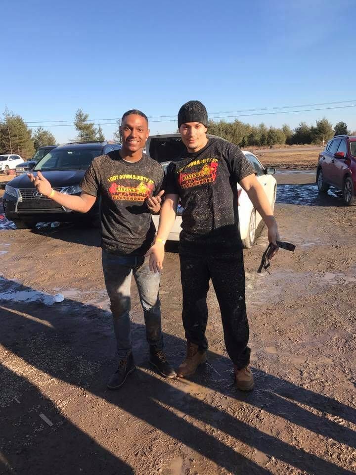Two men are standing next to each other in a parking lot.