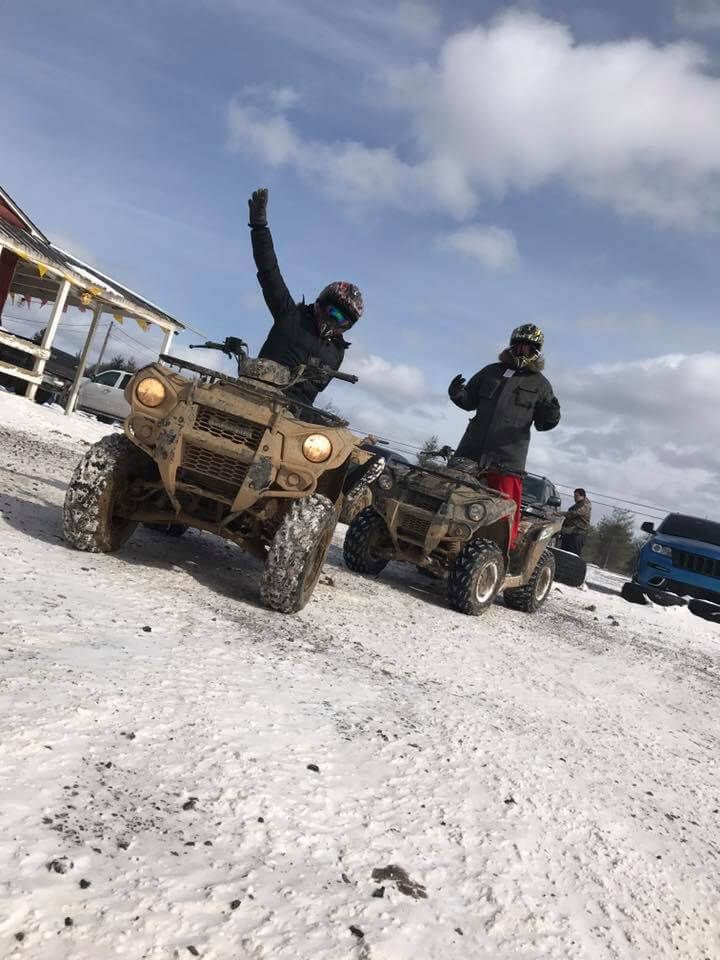 Two people are riding atvs in the snow.
