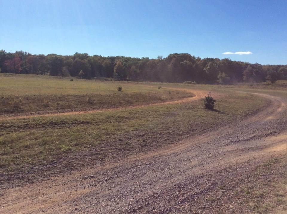 A tractor is driving down a dirt road in a field.