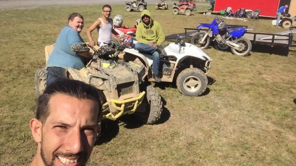 A group of men are sitting on atvs in a grassy field.