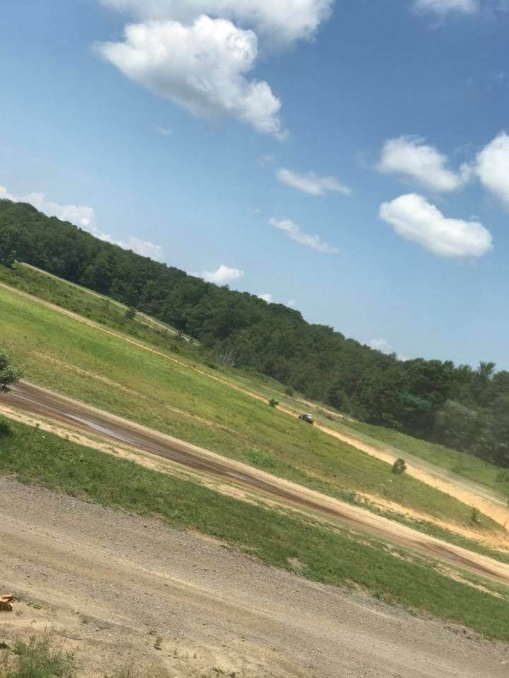 A dirt road going through a grassy hillside.