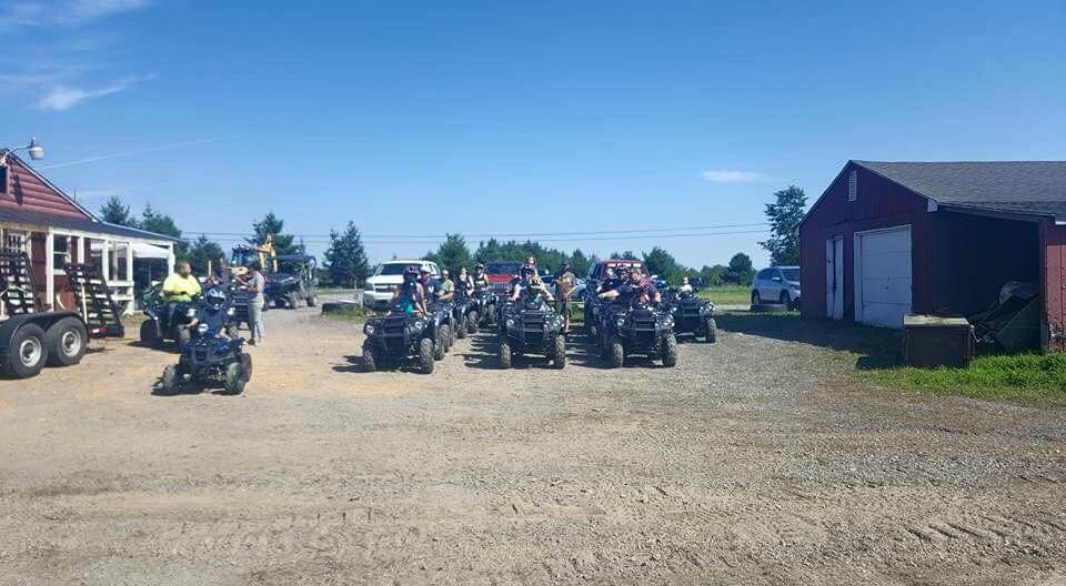 A group of people are riding atvs in a dirt lot.