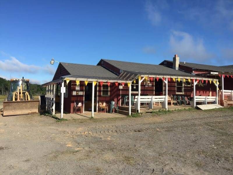 A large red house with a porch and a bulldozer in the background