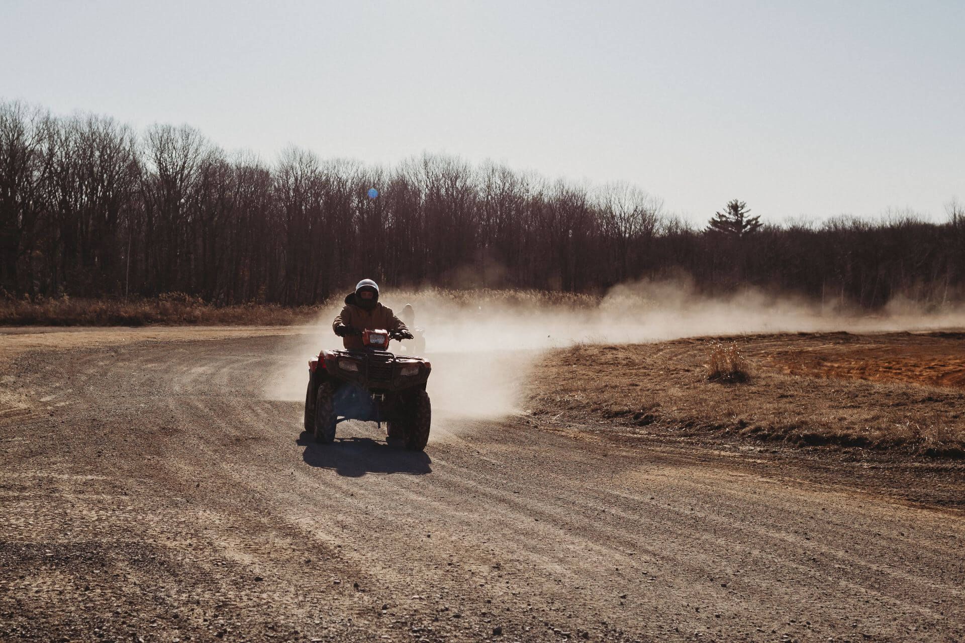 A person is riding an atv on a dirt road.