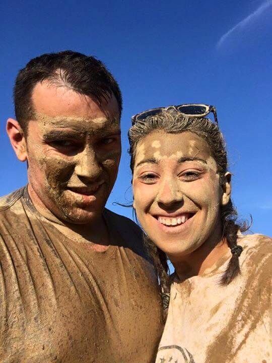 A man and a woman are standing next to each other with mud on their faces.