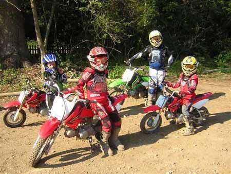 A group of people are standing next to each other on dirt bikes.