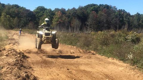 A person is riding an atv on a dirt road.