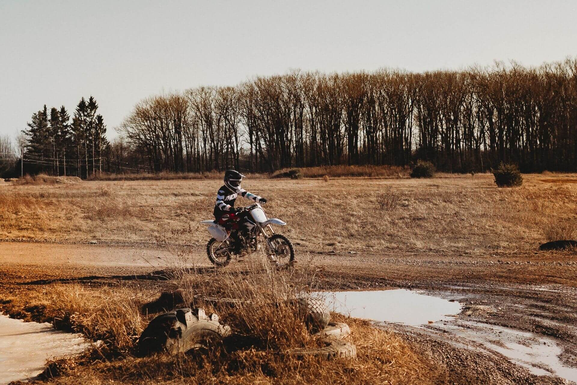 A person is riding a dirt bike through a muddy field.