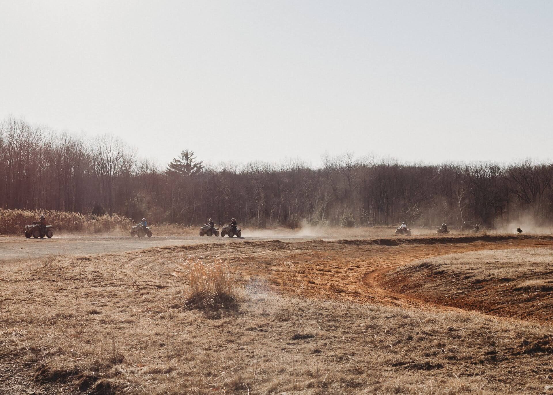 A group of people are riding atvs down a dirt road.