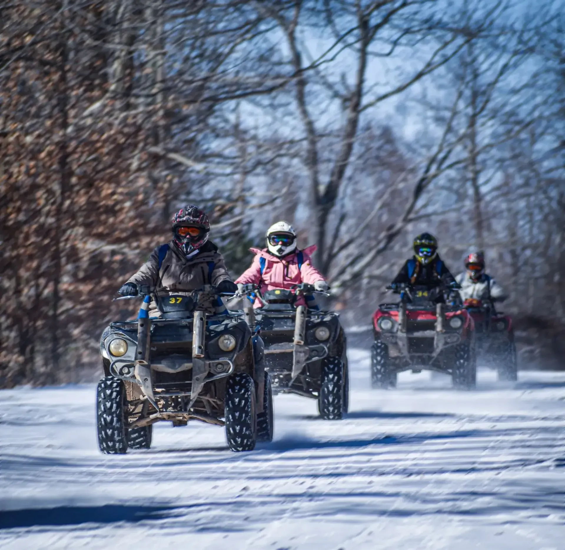 A group of people are riding atvs in the snow.