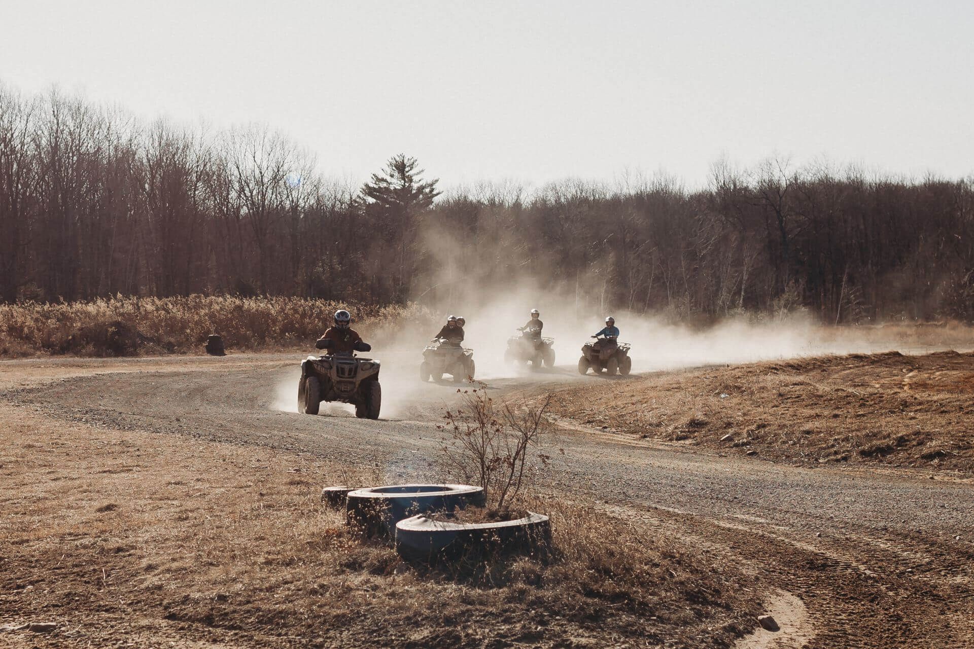 A group of people are riding atvs on a dirt road.