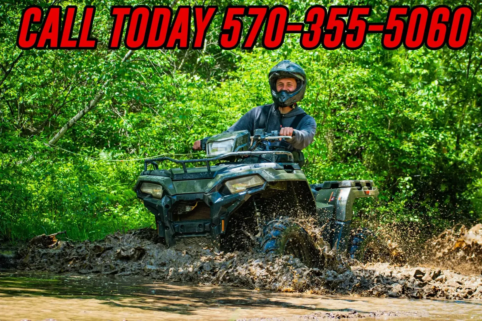 A man is riding a four wheeler through the mud.