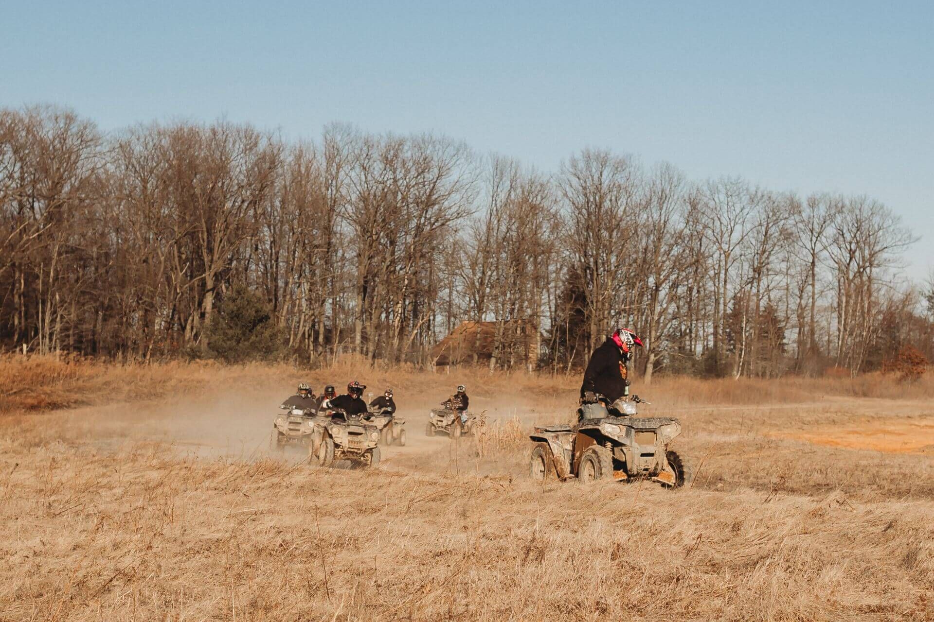 A group of people are riding atvs in a field.