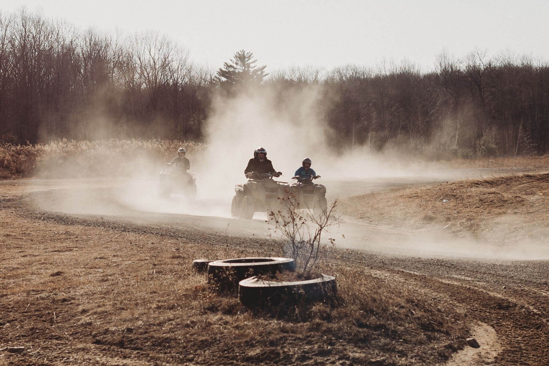 A group of people are riding atvs on a dirt road.