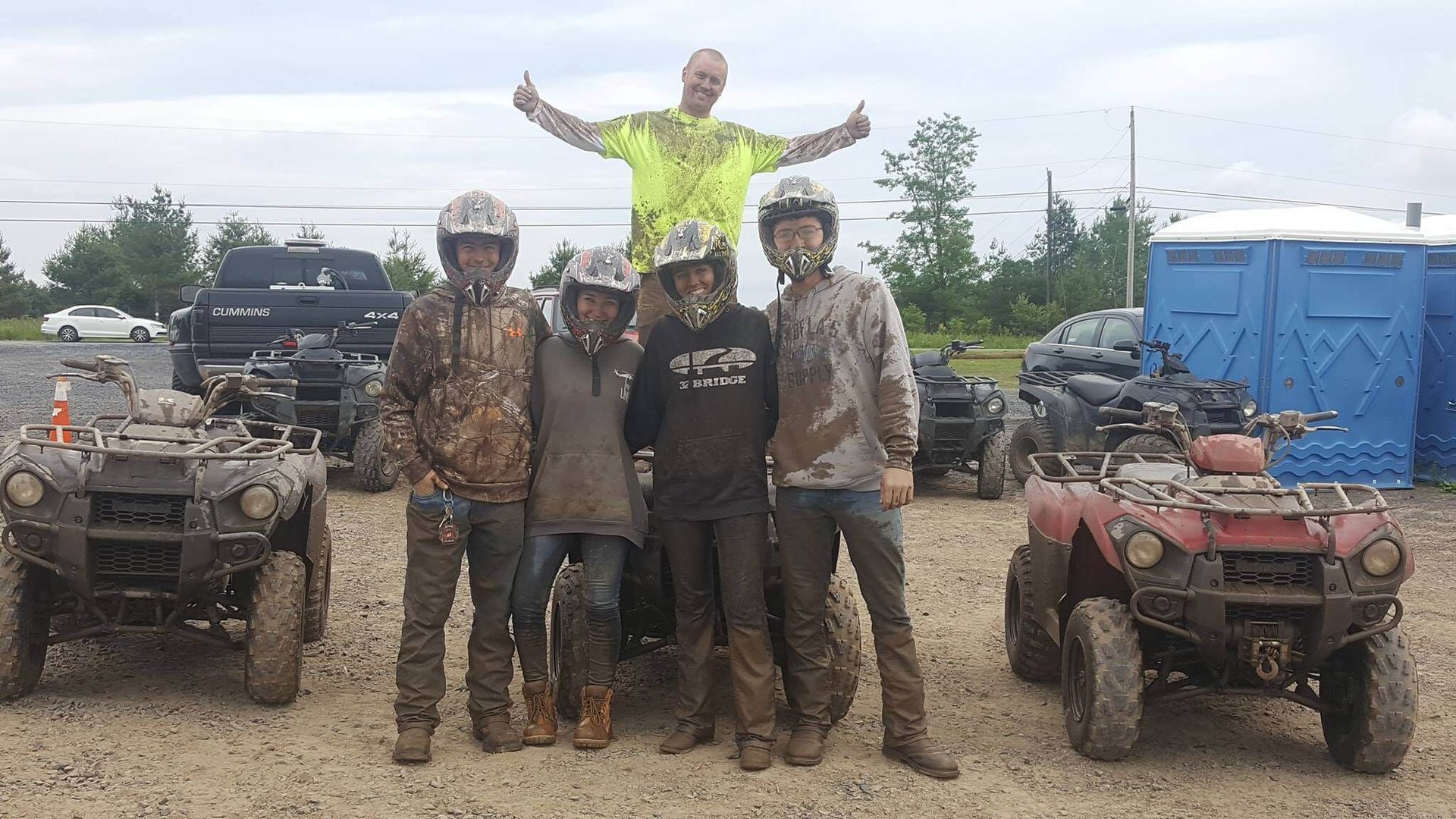 A group of people are posing for a picture in front of atvs.
