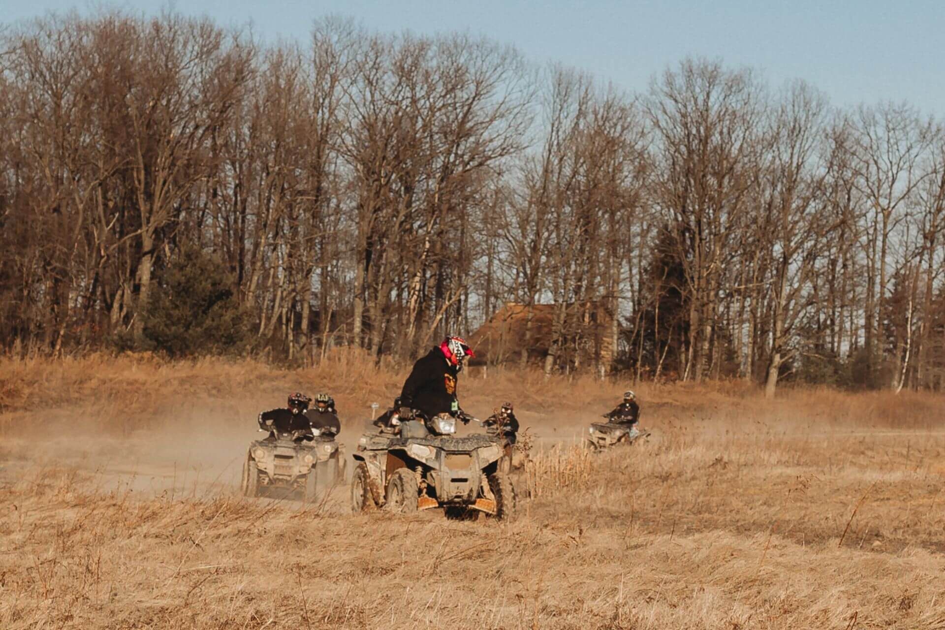 A group of people are riding atvs in a field.