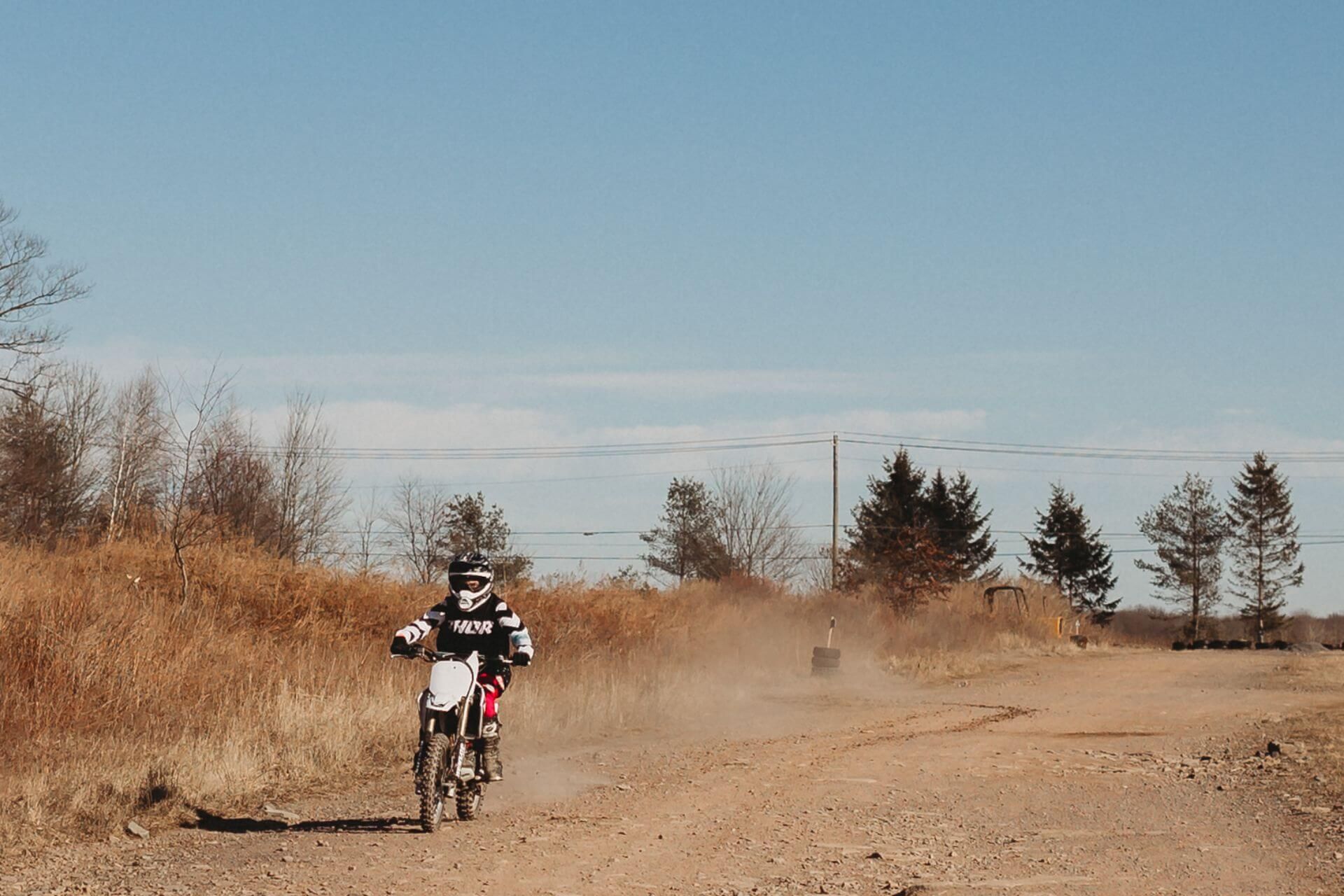 A person is riding a dirt bike on a dirt road.