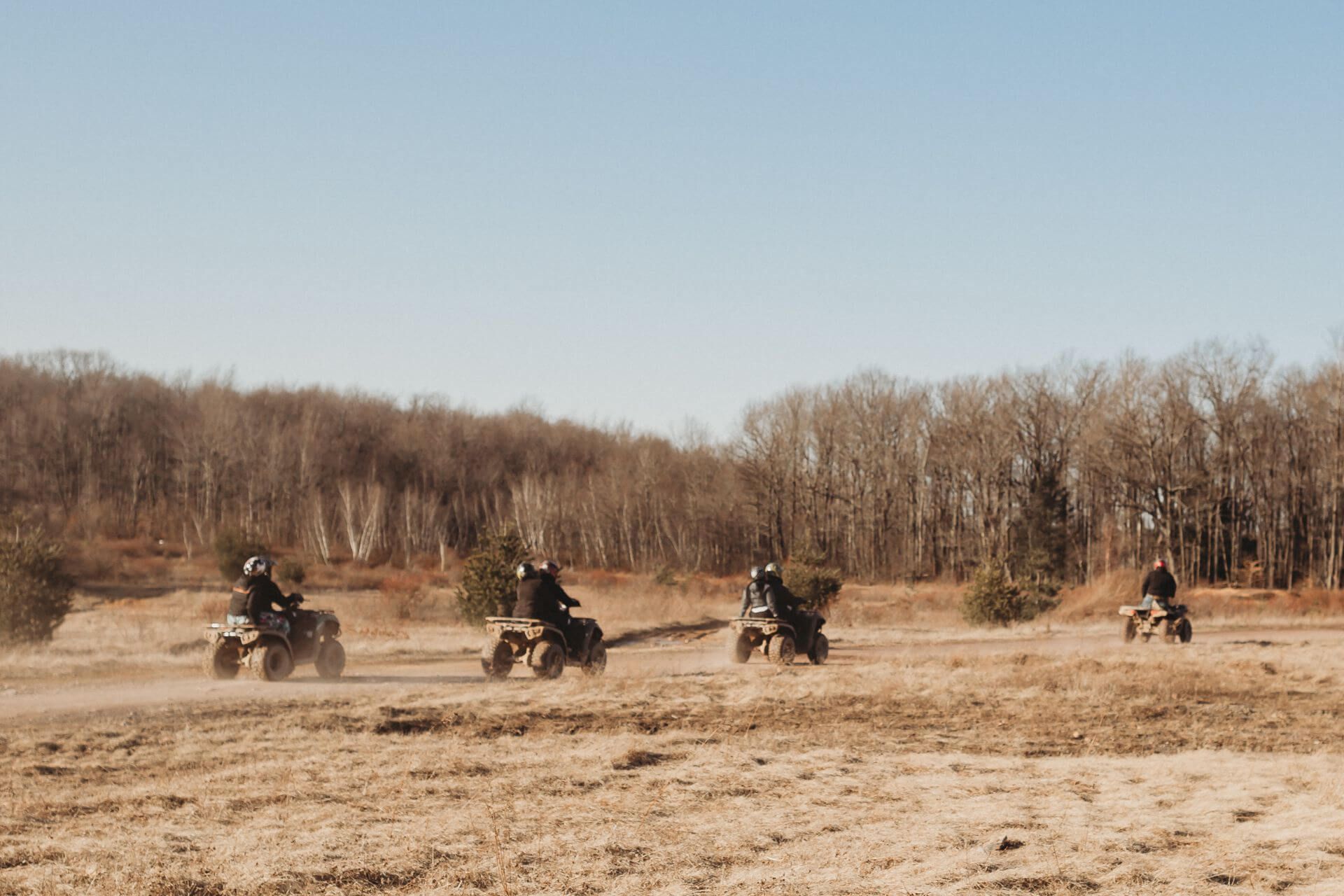 A group of people are riding atvs in a field.