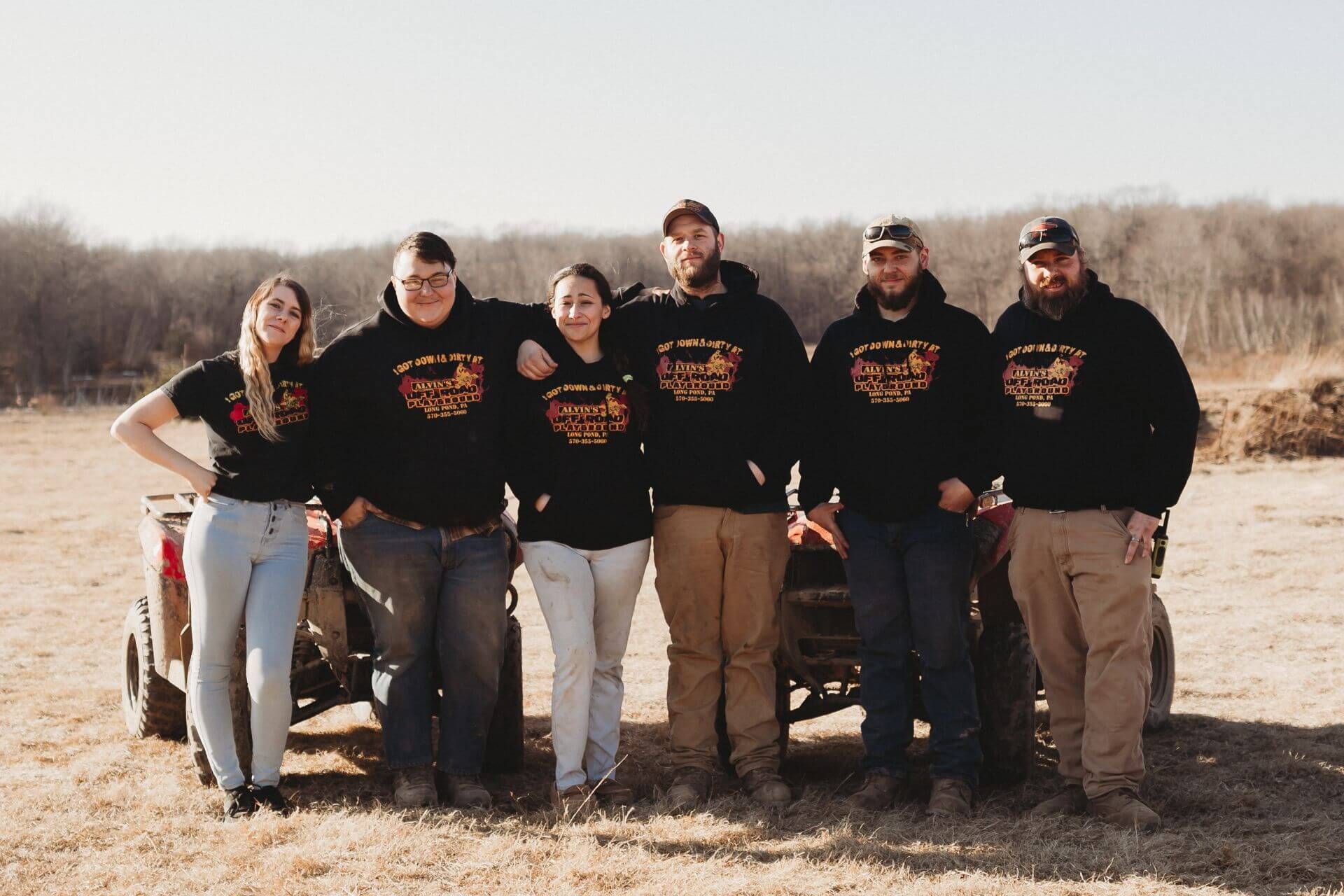 A group of people are posing for a picture in front of an atv.
