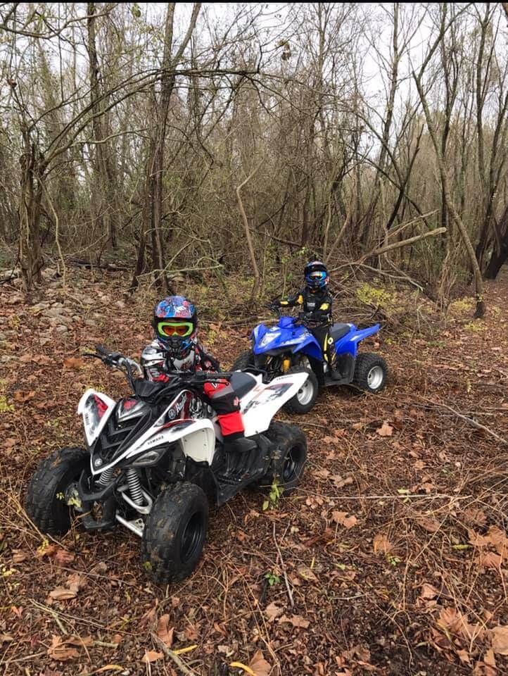 Two atvs are parked next to each other in the woods.