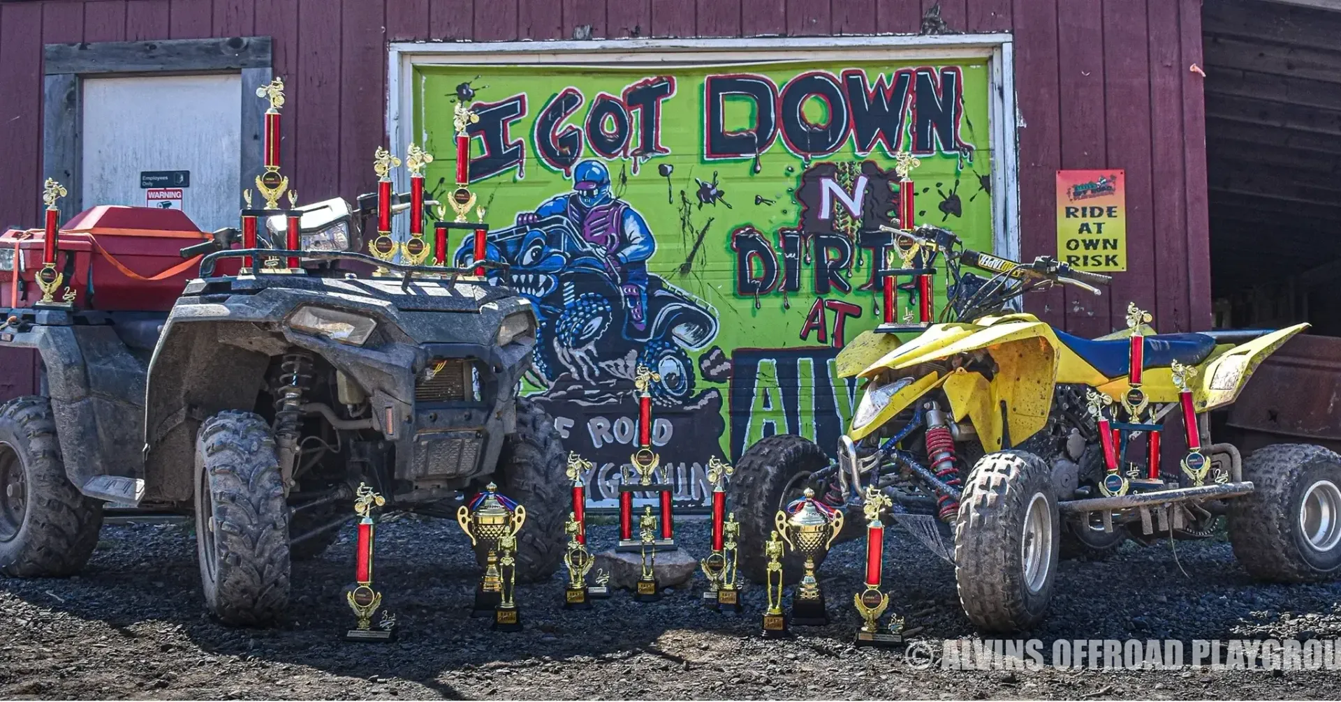Several atvs are parked in front of a sign that says get down in the dirt
