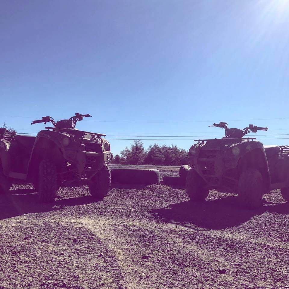 Two atvs are parked next to each other on a dirt road