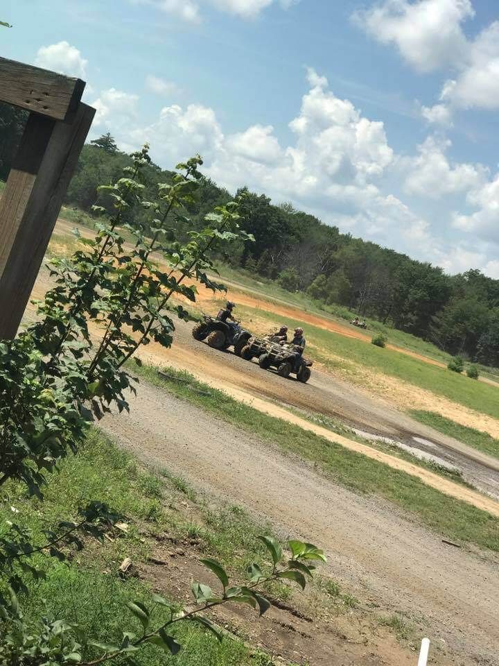 A group of people are riding atvs down a dirt road.