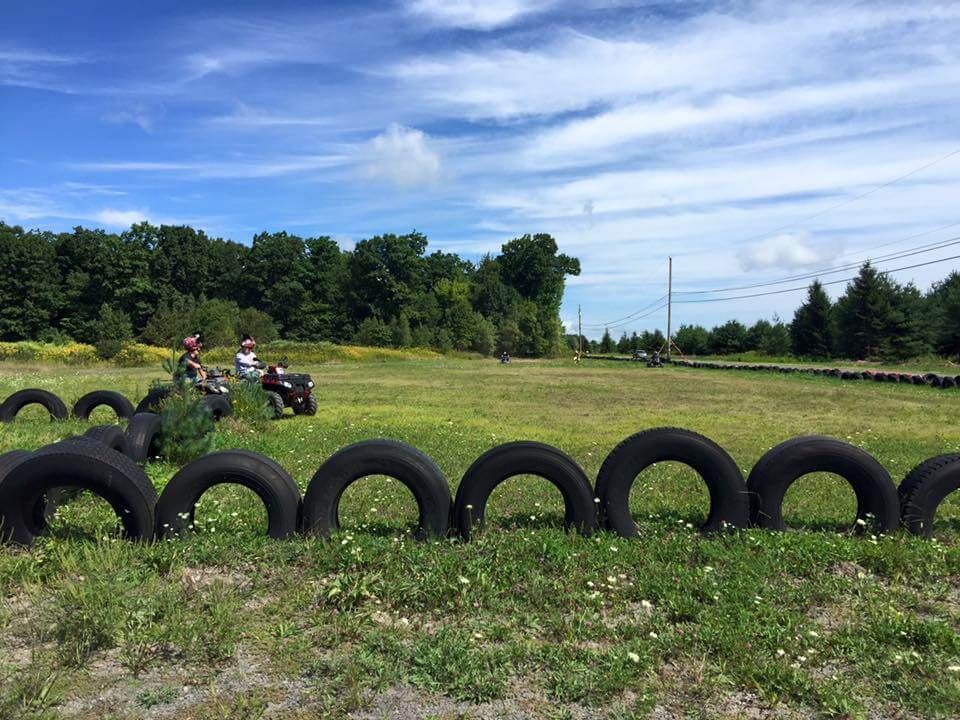 A group of people are riding atvs in a field surrounded by tires.