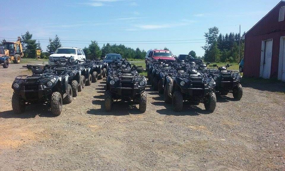 A bunch of atvs are parked in a gravel lot