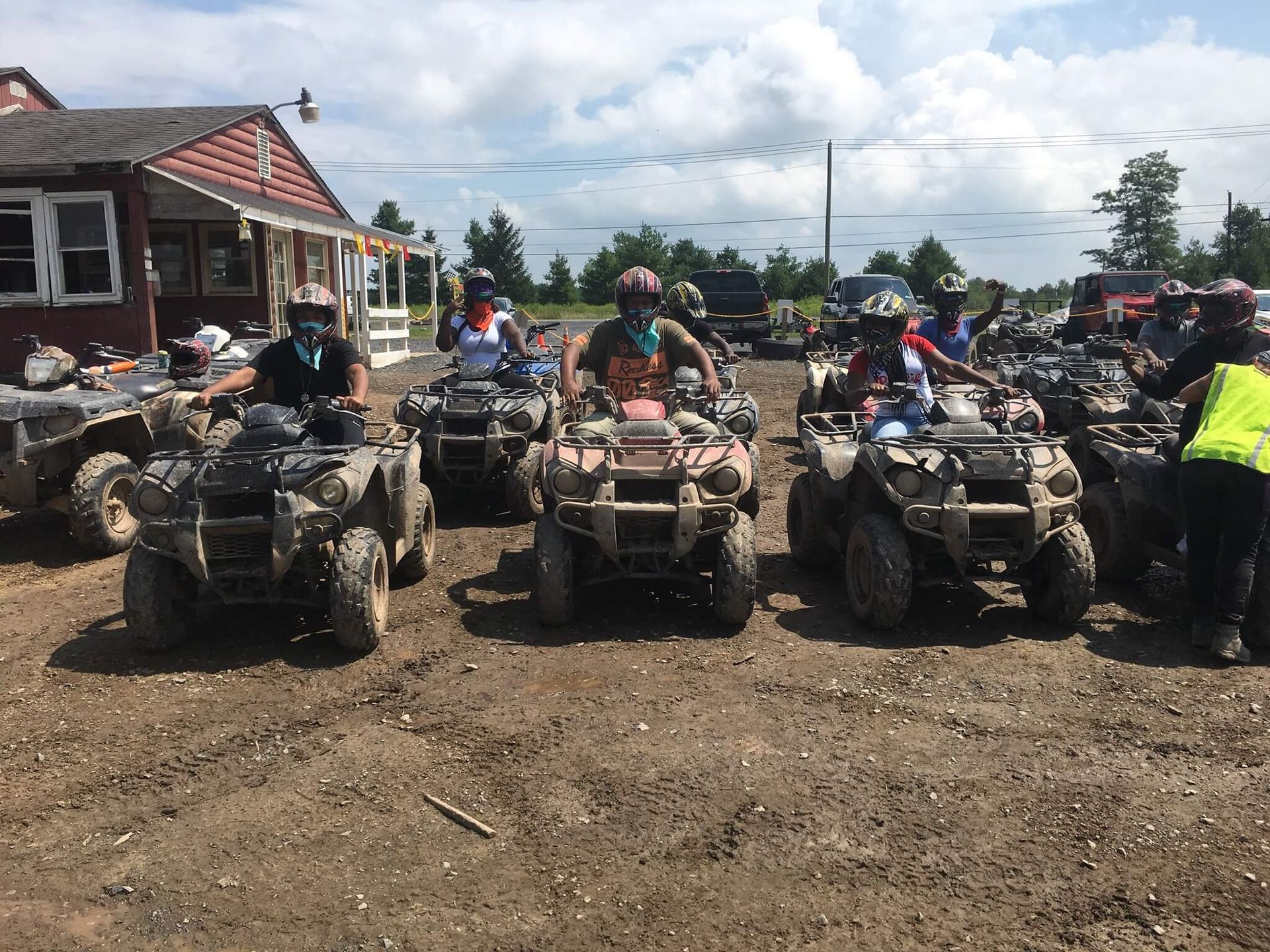 A group of people are riding atvs in a dirt field.
