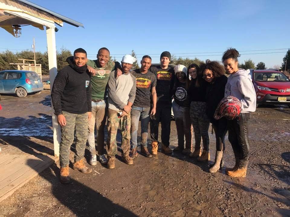 A group of people are posing for a picture in a parking lot.