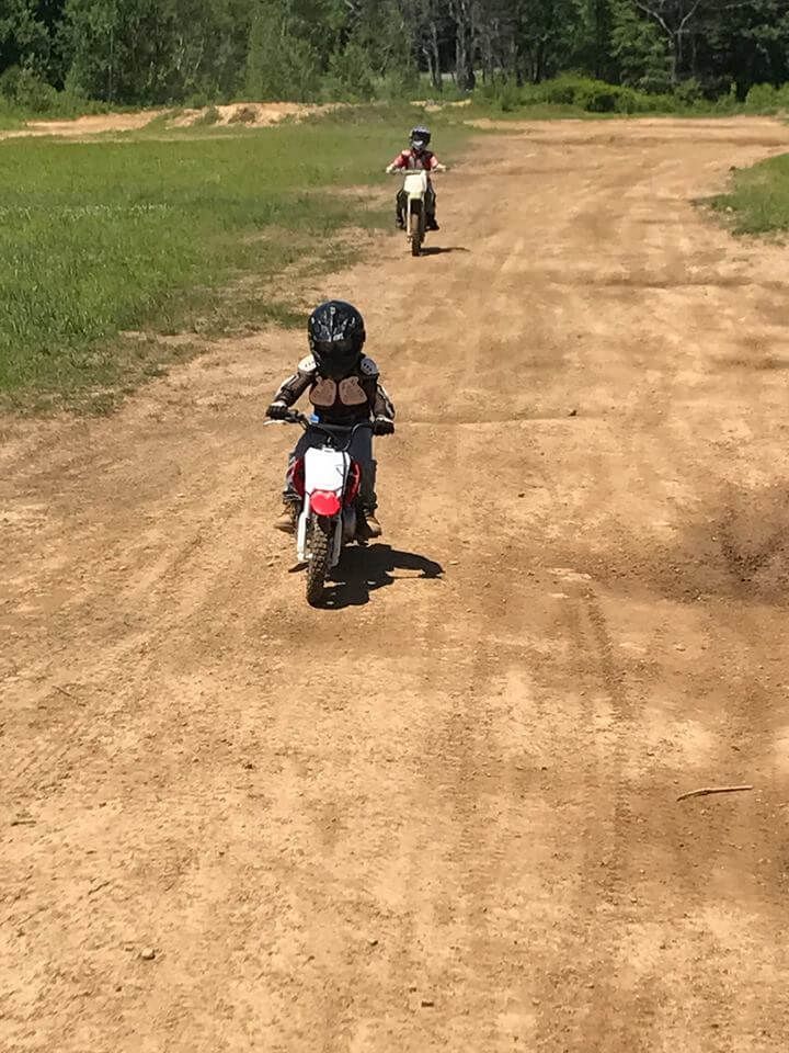 Two people are riding dirt bikes on a dirt road.
