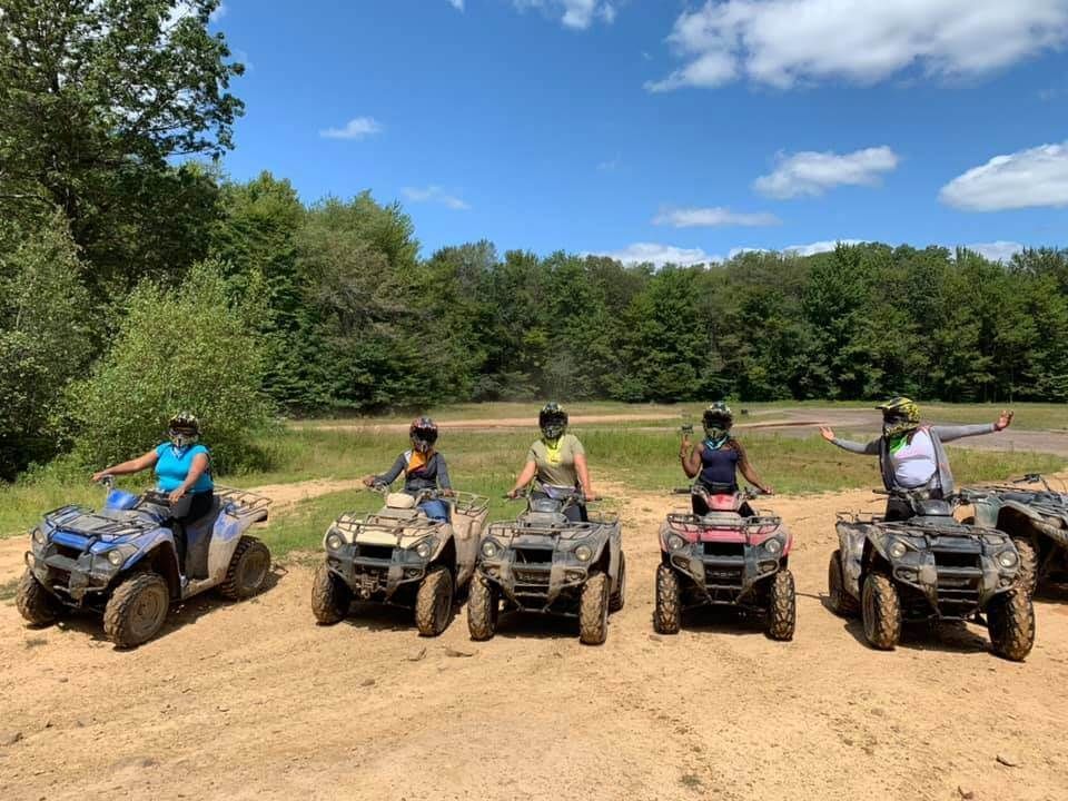 A group of people are riding atvs in a dirt field.
