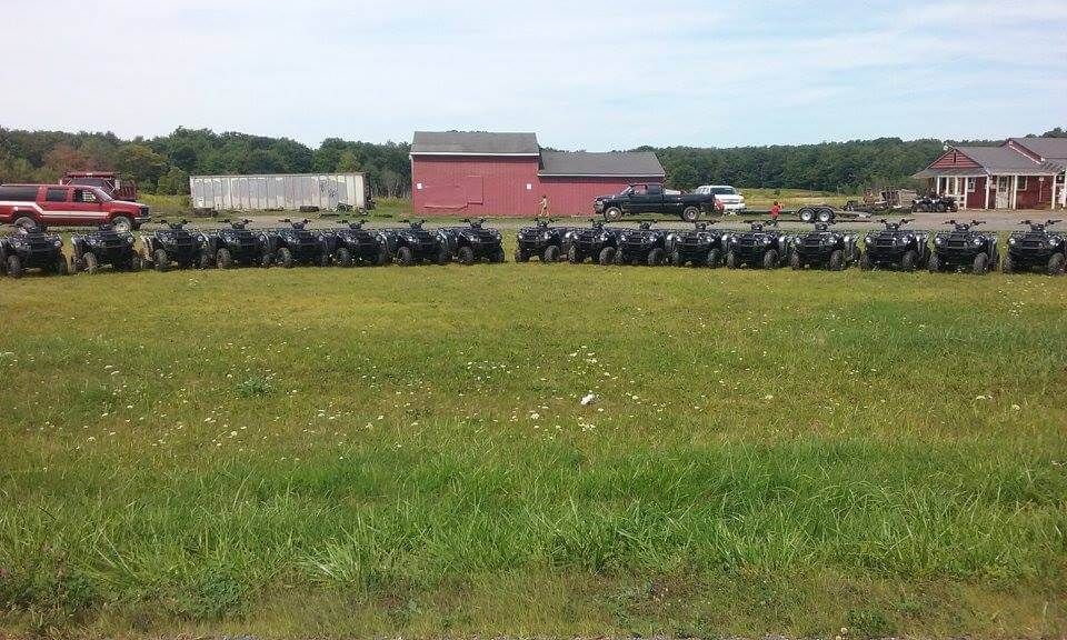 A row of motorcycles are parked in a grassy field