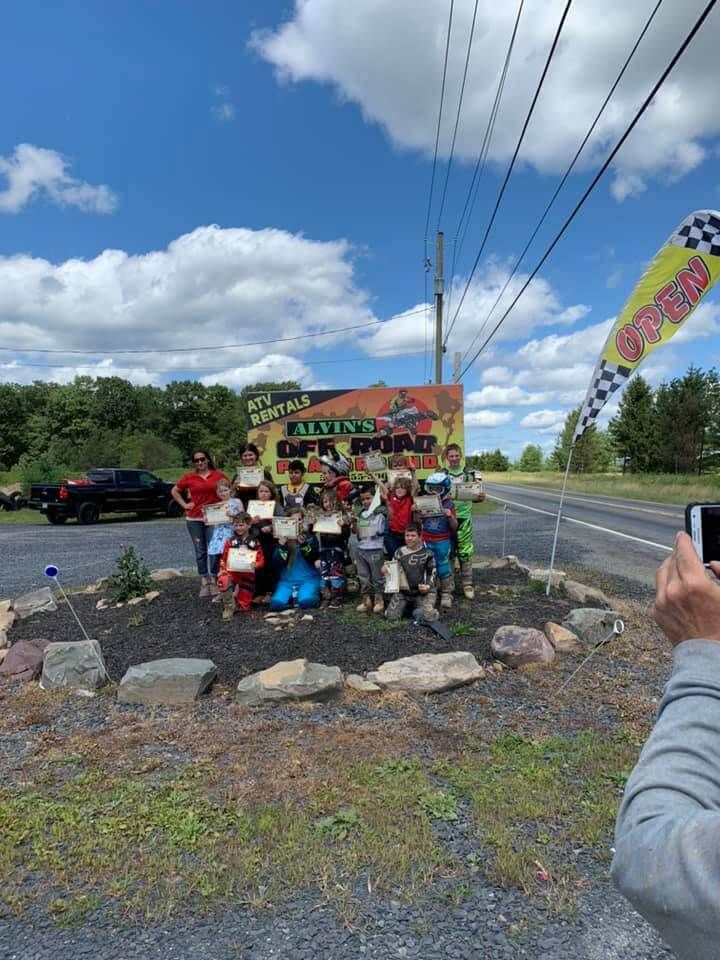 A person is taking a picture of a group of people standing in front of a sign.