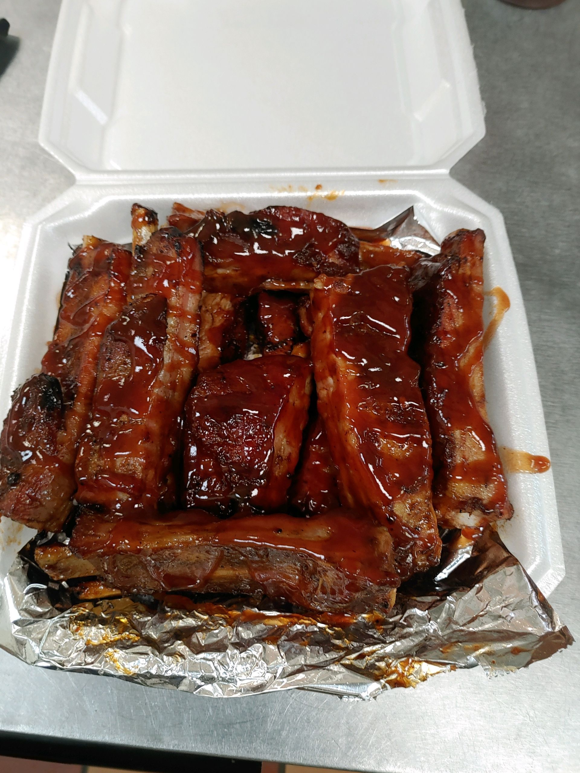 A styrofoam container filled with barbecue ribs