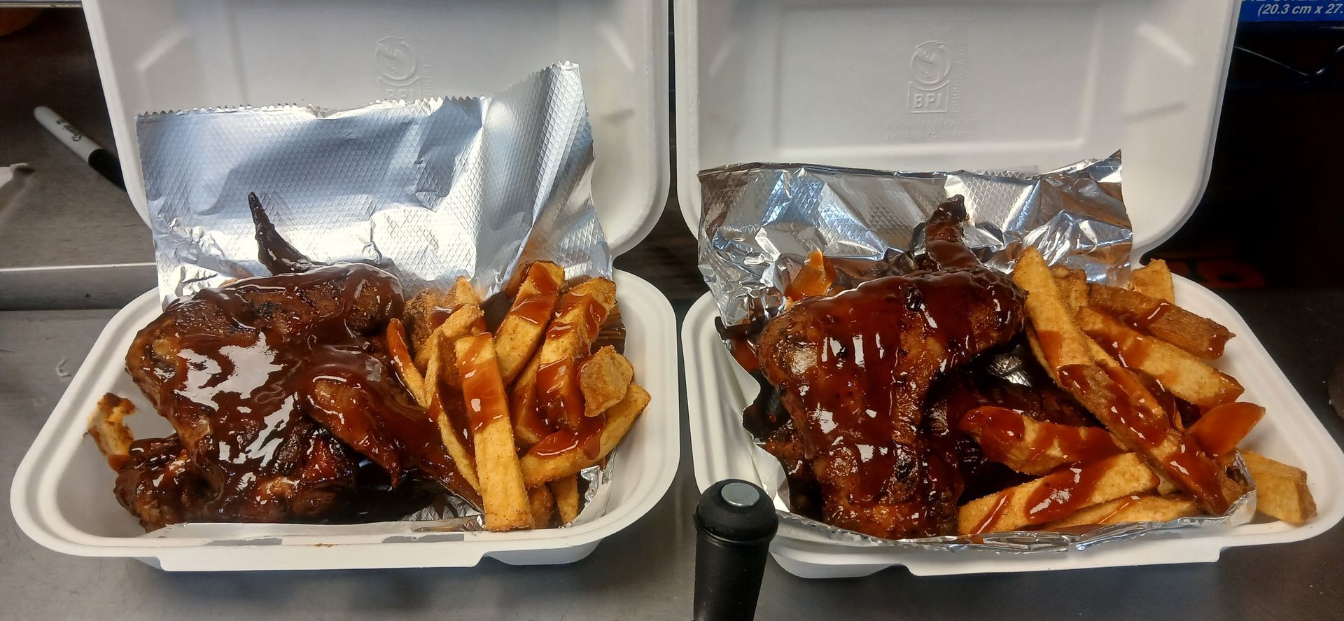 Two styrofoam containers filled with chicken wings and french fries