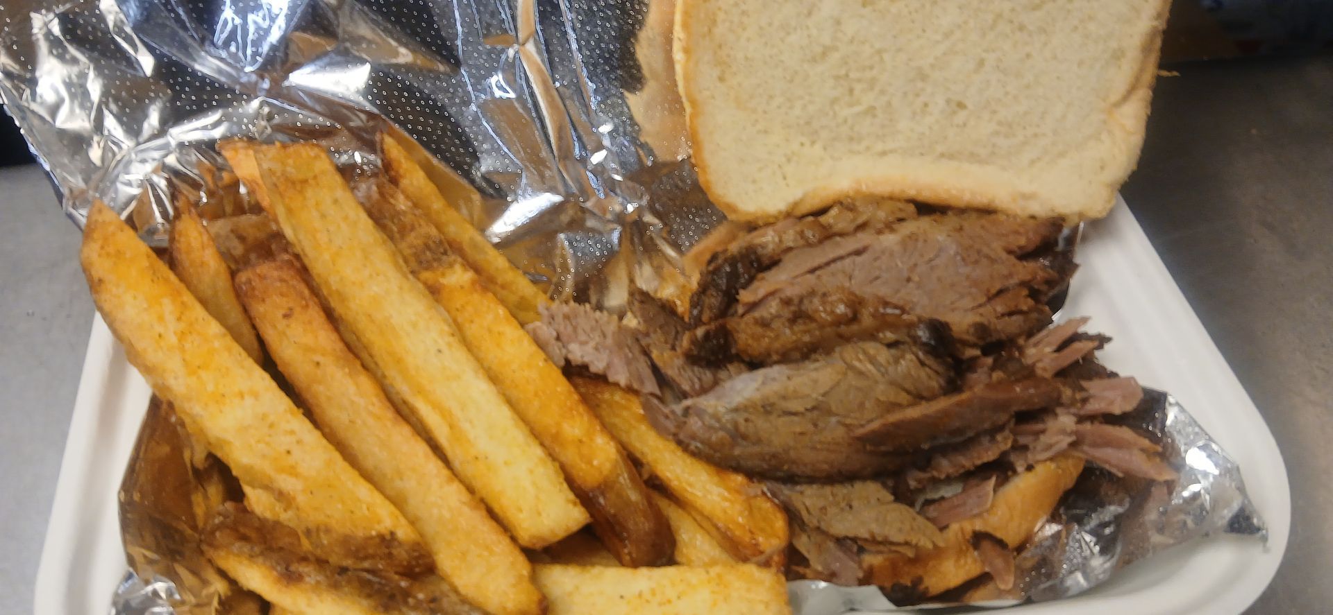 A sandwich and french fries in a styrofoam container.
