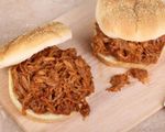 Two pulled pork sandwiches on a wooden cutting board