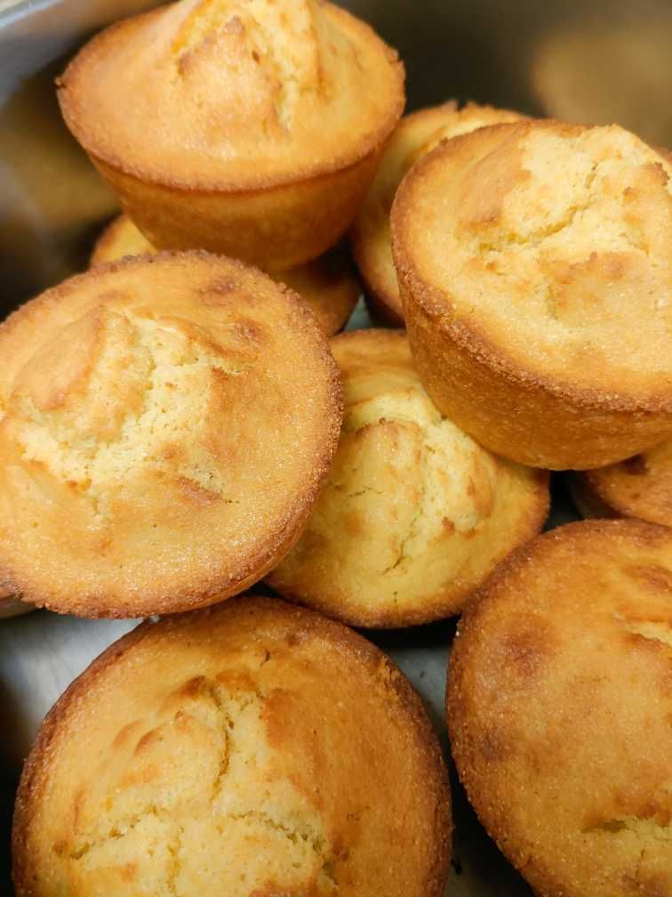 A bunch of corn muffins are sitting on top of each other on a table.
