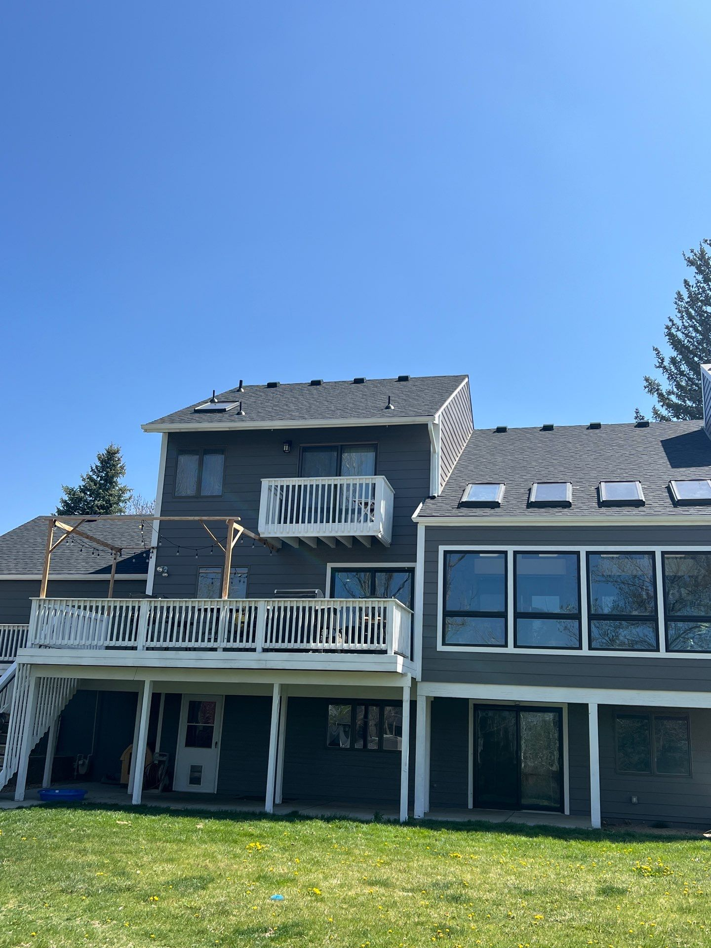 A large house with a large deck and a large lawn in front of it.