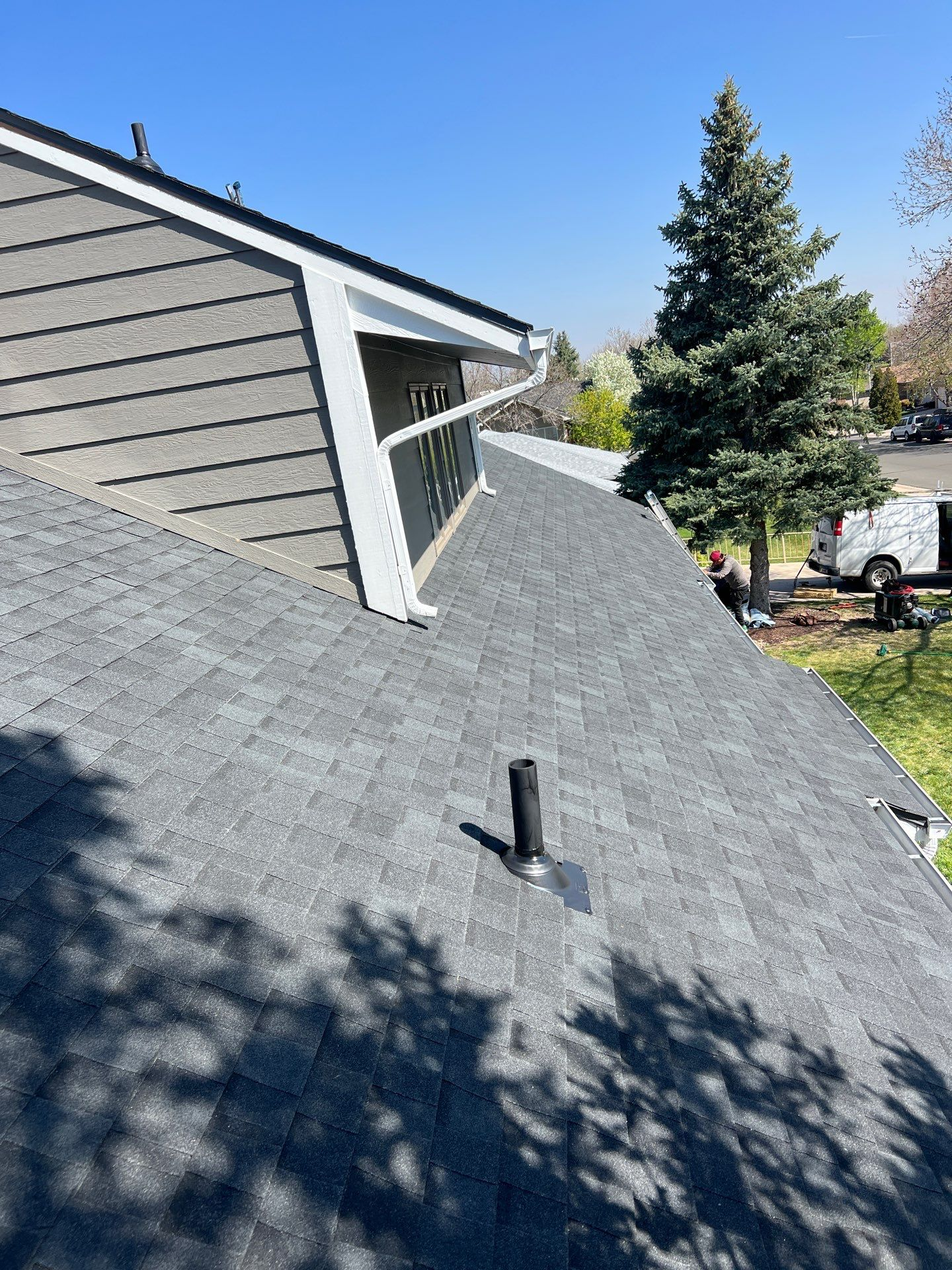 A close up of a roof of a house with a tree in the background.