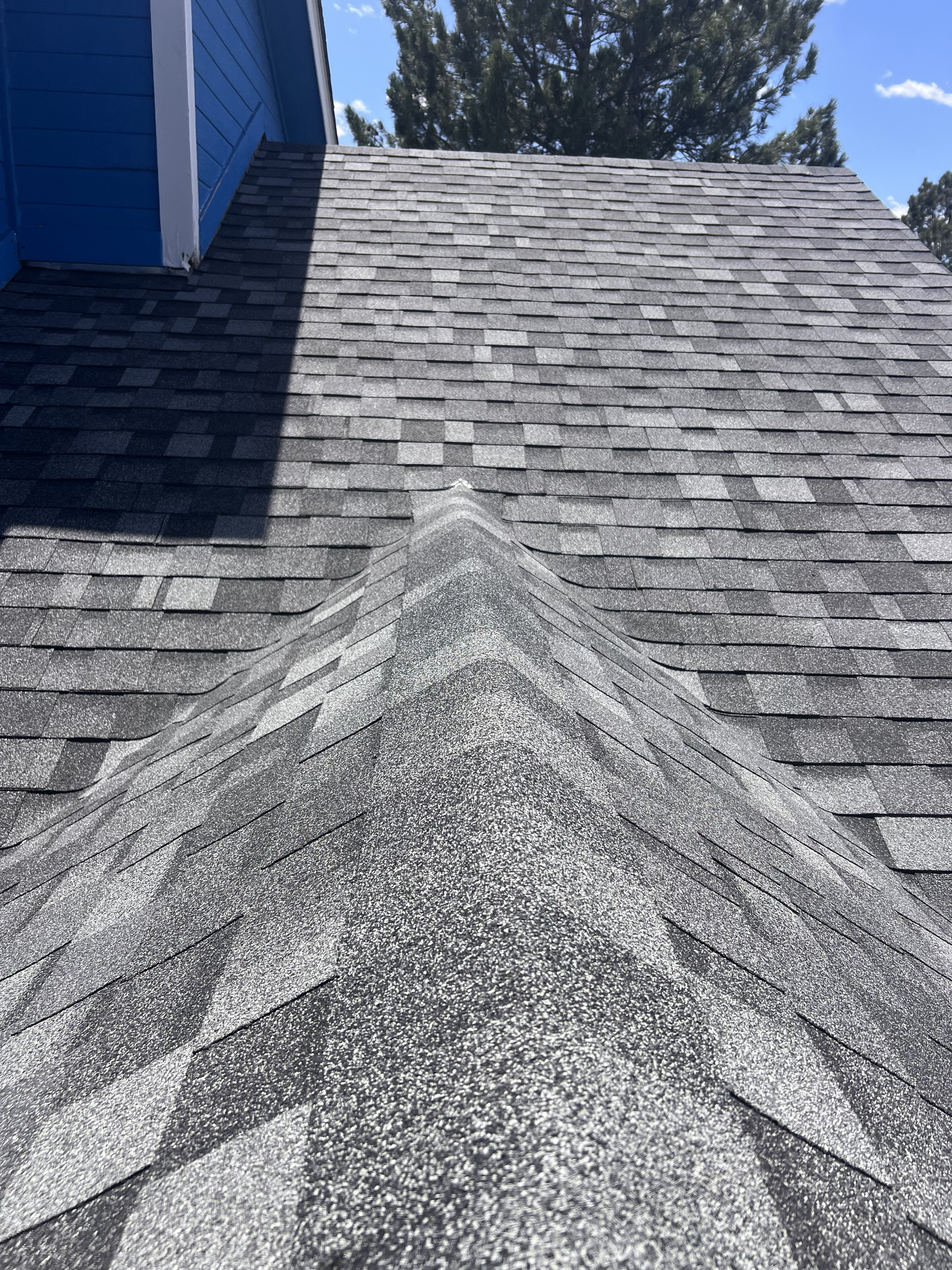 A close up of a roof with a blue building in the background.