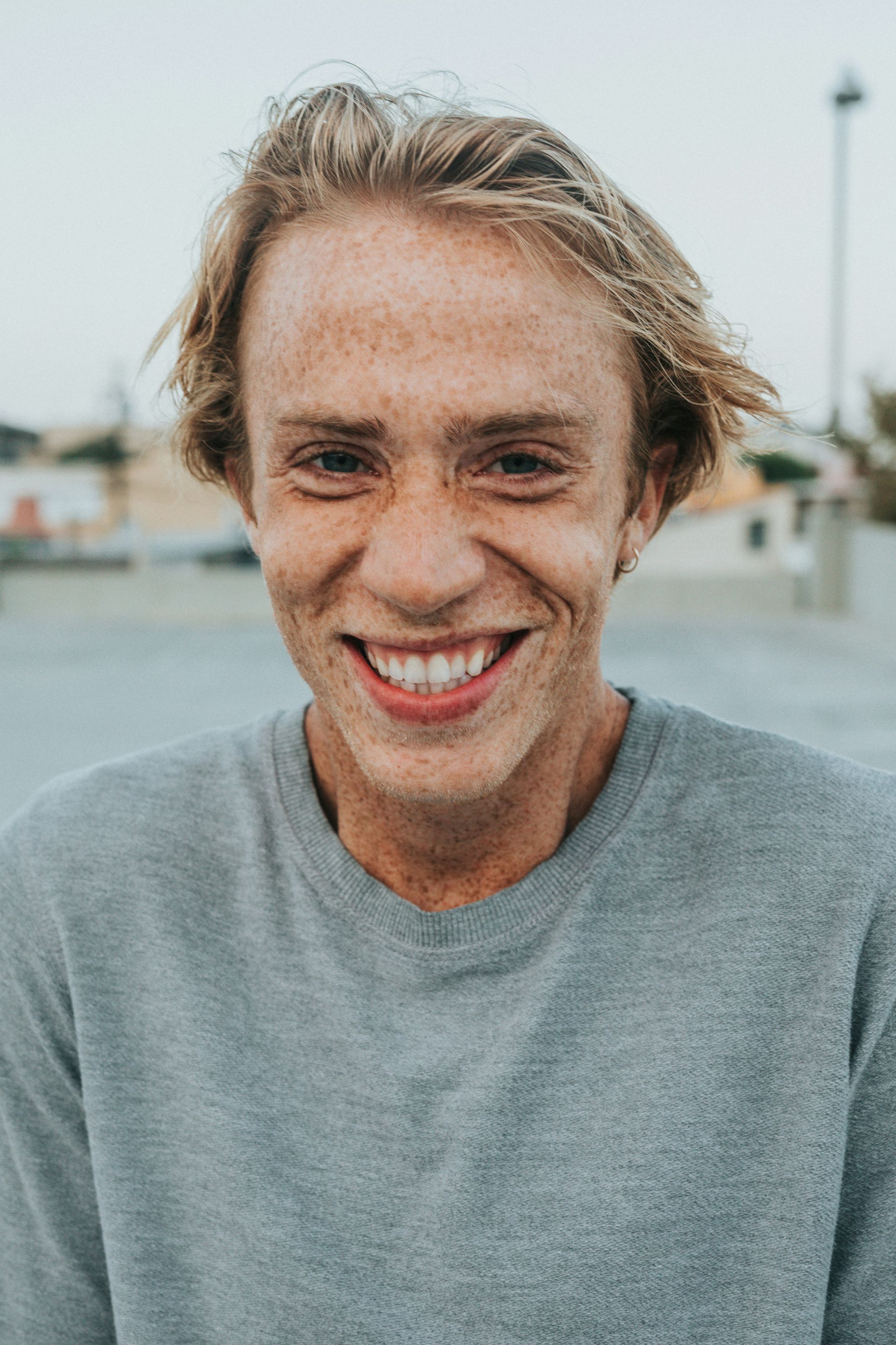 A young man with freckles is smiling for the camera.