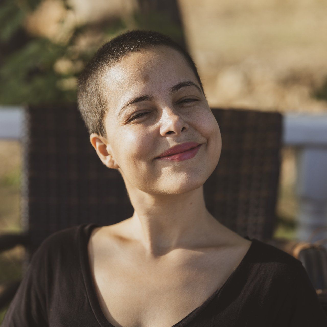 A woman with short hair is smiling and wearing a black shirt