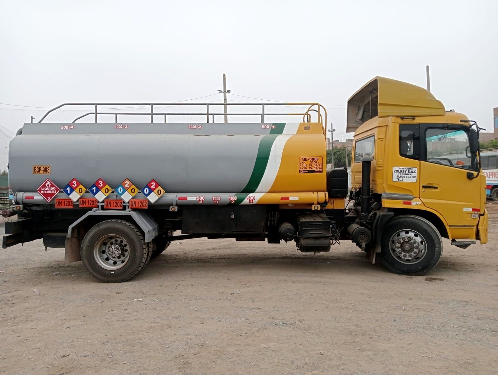 Un camión cisterna amarillo está estacionado en un lote de tierra.